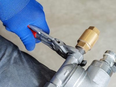 Installation of heating and water supply systems. A plumber tightens nuts on a metal pipeline using a wrench. Unrecognizable person. selective focus